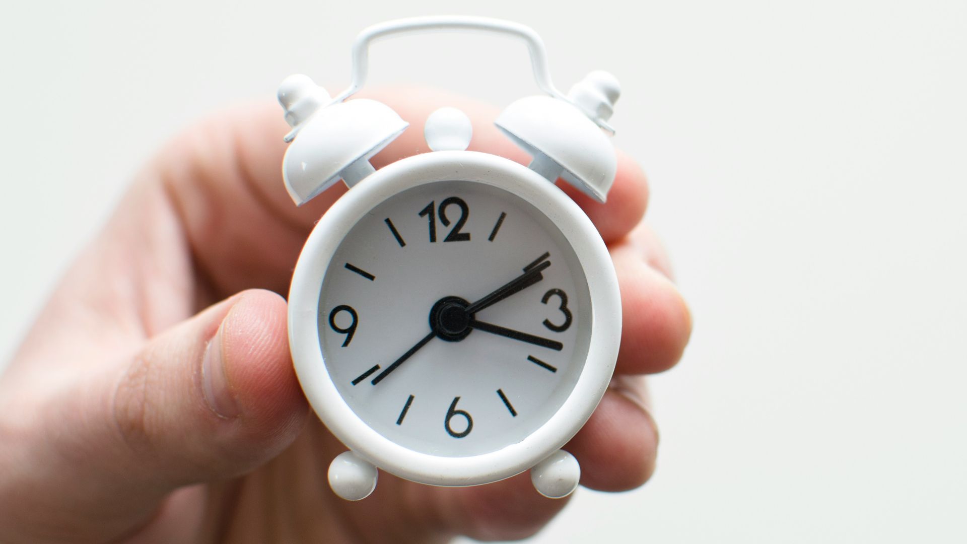 person holding white mini bell alarmclock