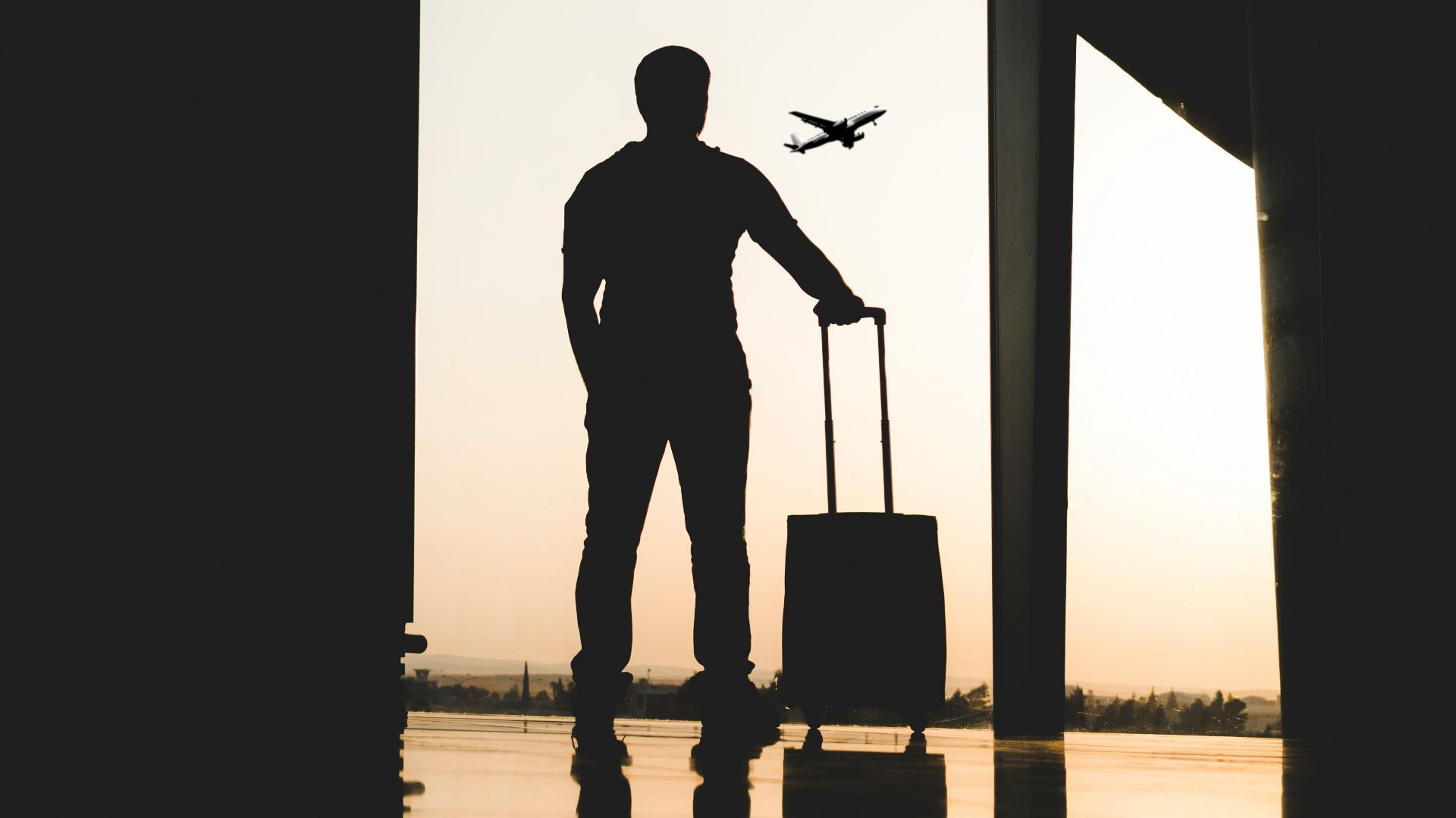 silhouette of man holding luggage inside airport