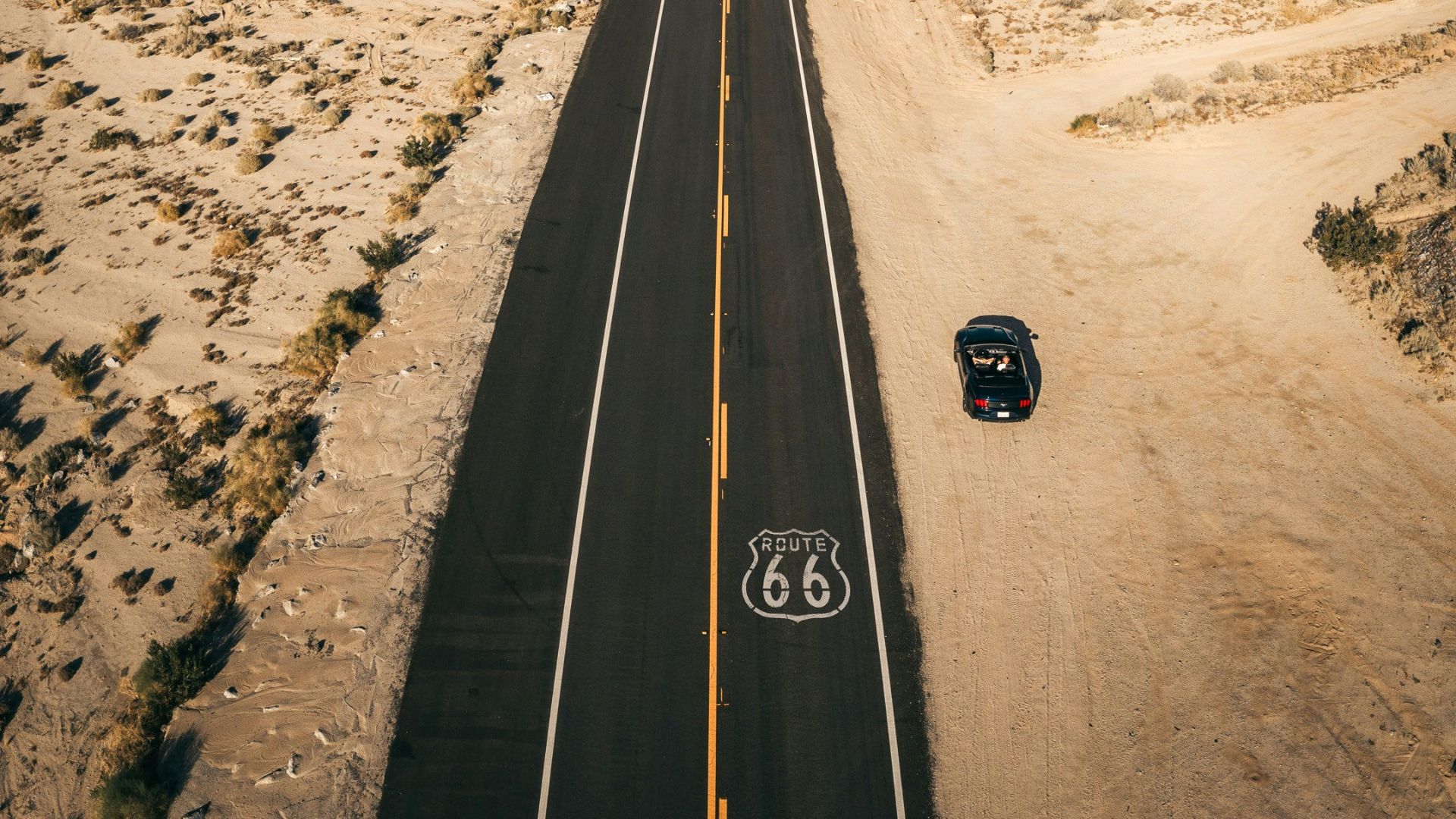 a car driving down a road in the middle of the desert