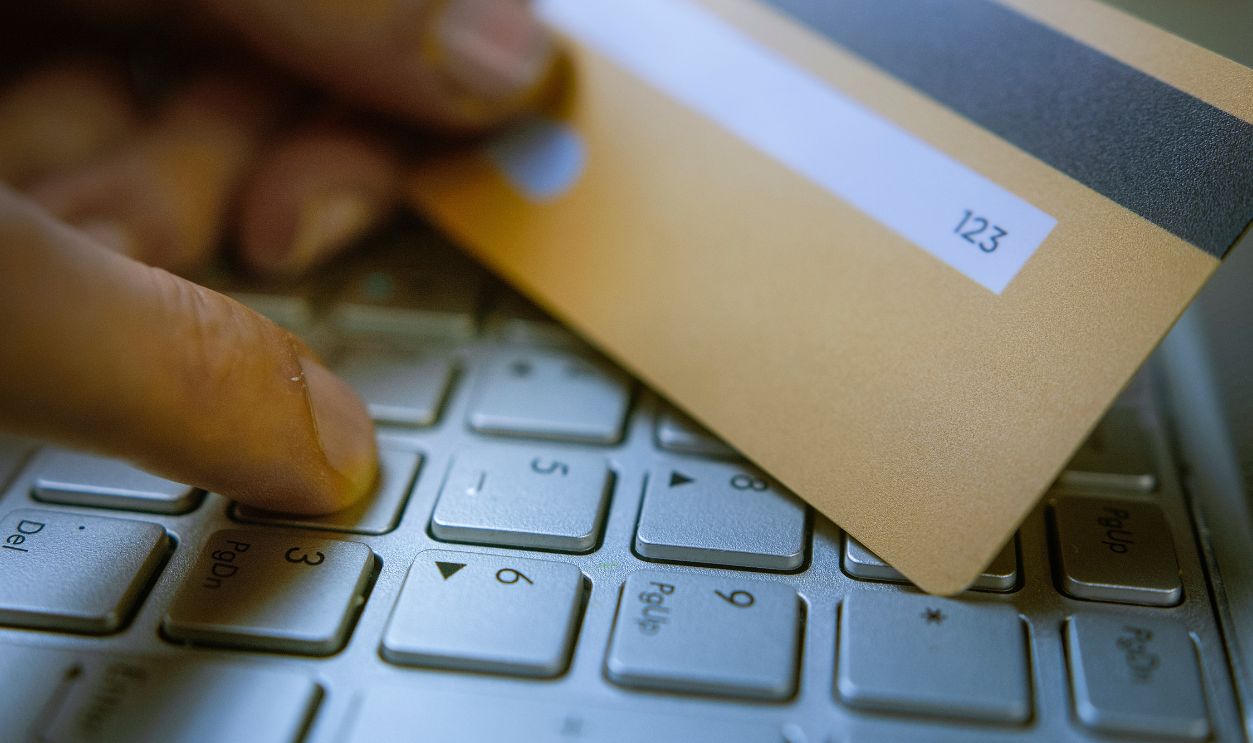 Entering CVVCVC code on a laptop keyboard with a credit card in hand, online payment security, cyber fraud risk, digital transactions, e-commerce safety