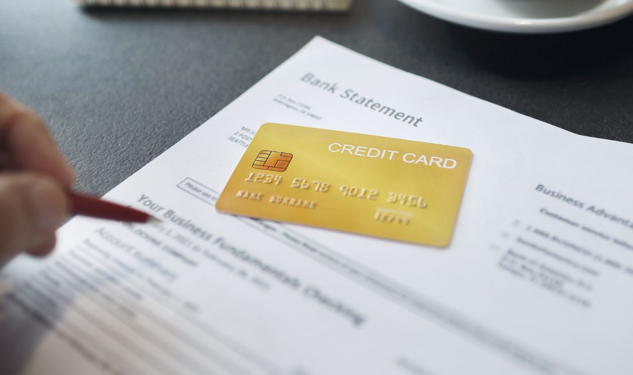Credit card with bank ststement report on desk, asian man verify the accuracy of bank statement after using credit card to pay for merchandise