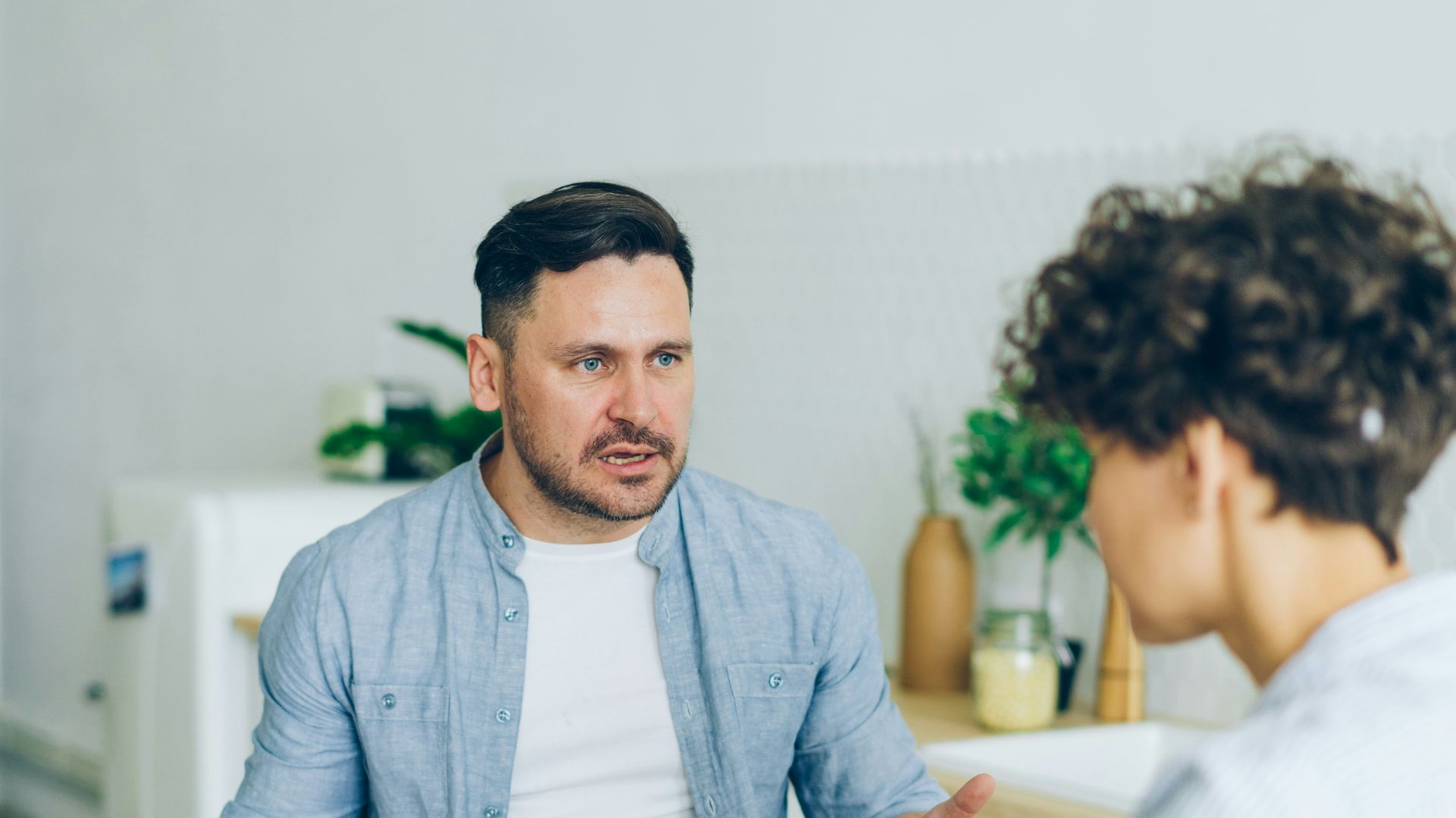 a man sitting at a table talking to a woman