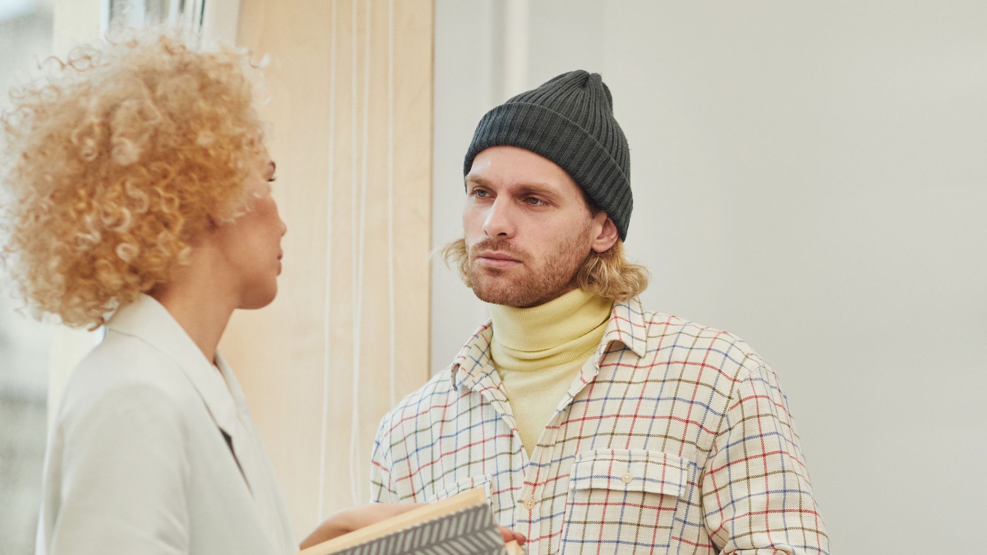 Two adults engaging in conversation holding a book in a modern office space, promoting teamwork and collaboration.