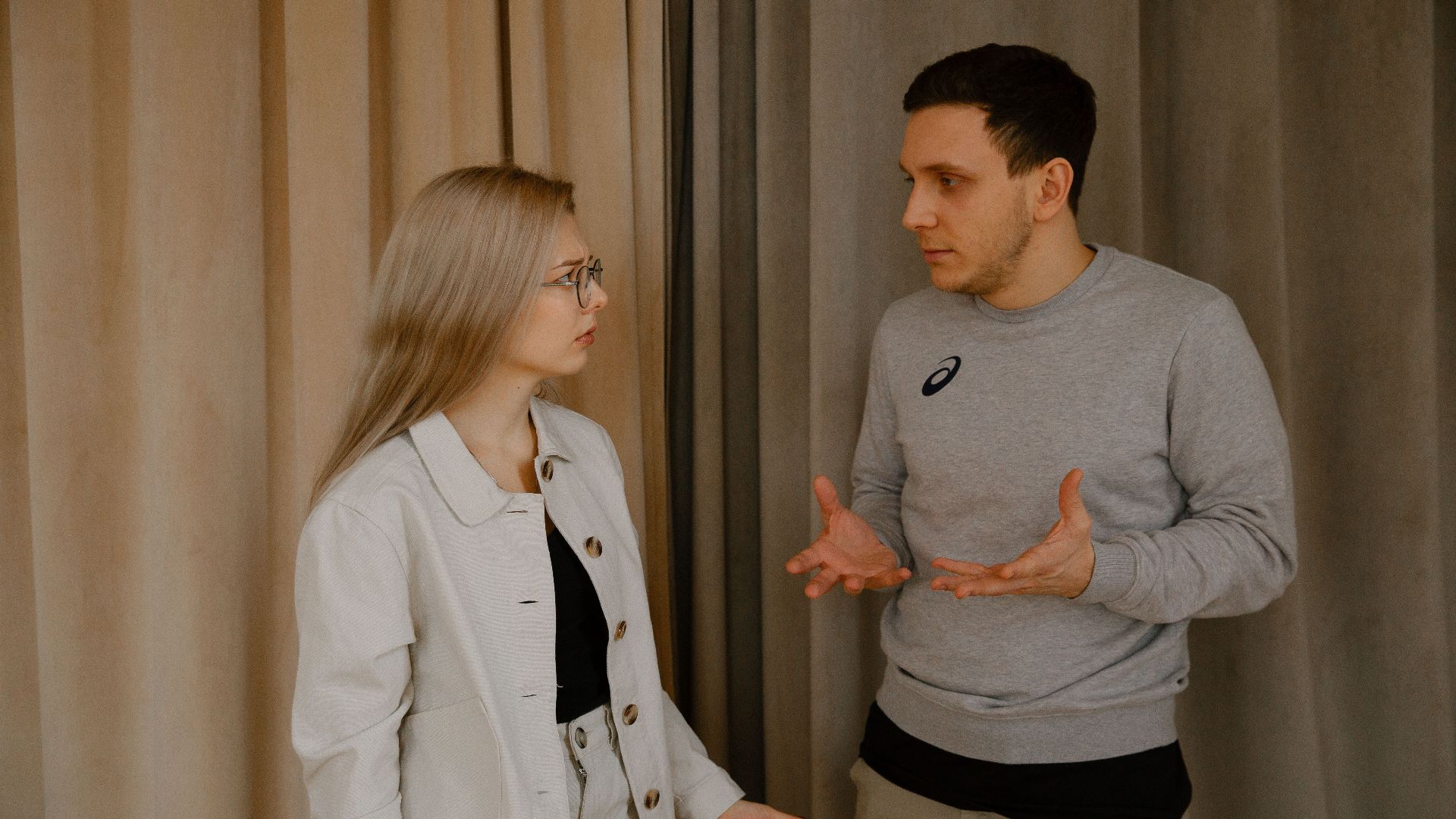 A young couple passionately discussing indoors, capturing intense emotions and gestures.