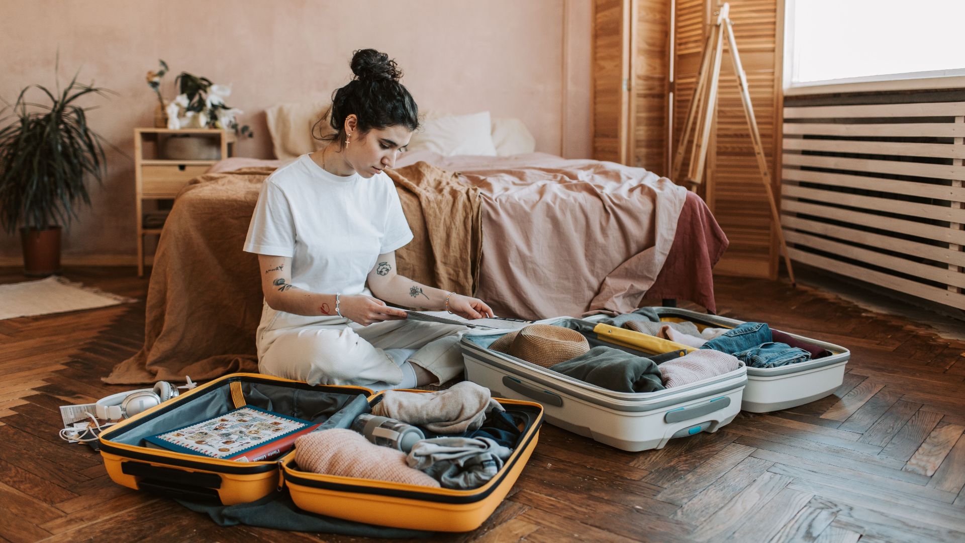 A woman organizes luggage in a stylish bedroom, carrying wanderlust vibes.