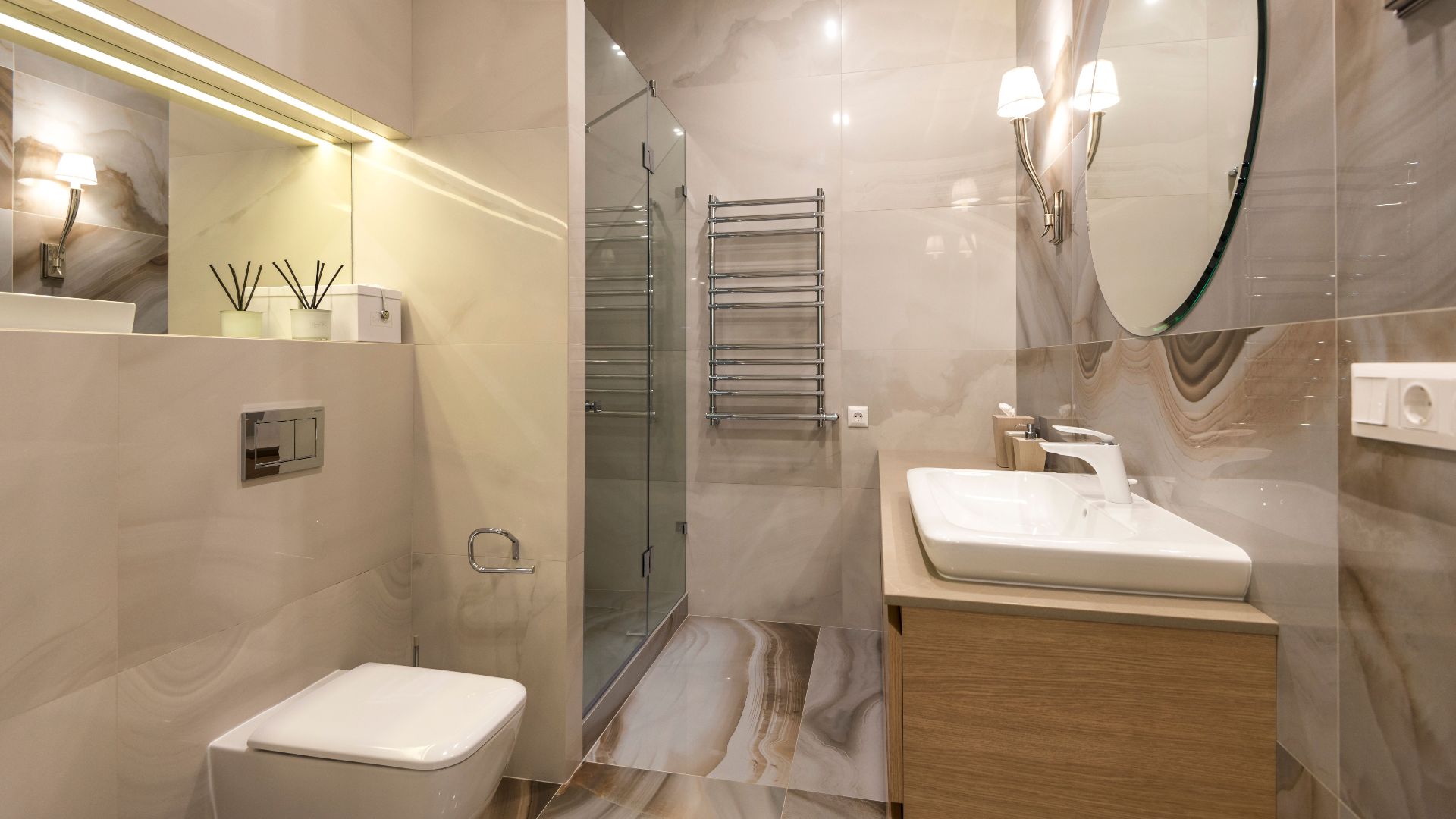 Elegant bathroom with marble tiles, large mirror, and modern fixtures.