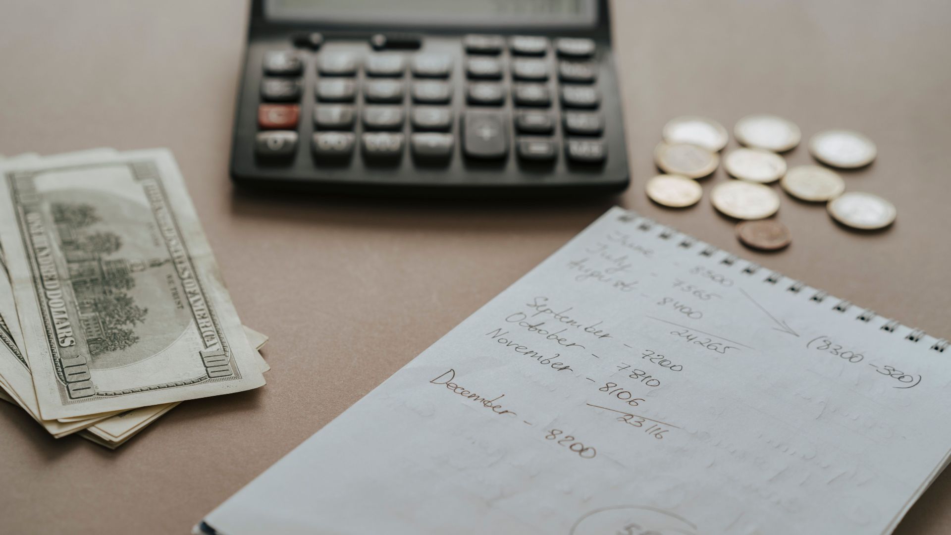 Desk setup showing calculator, cash, coins, and financial notes for budgeting.