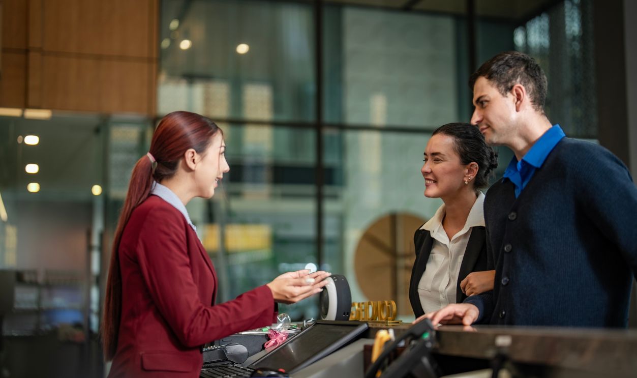 Receptionist assisting guests at modern front desk in luxury hotel. Ideal for customer service, travel, and tourism marketing.