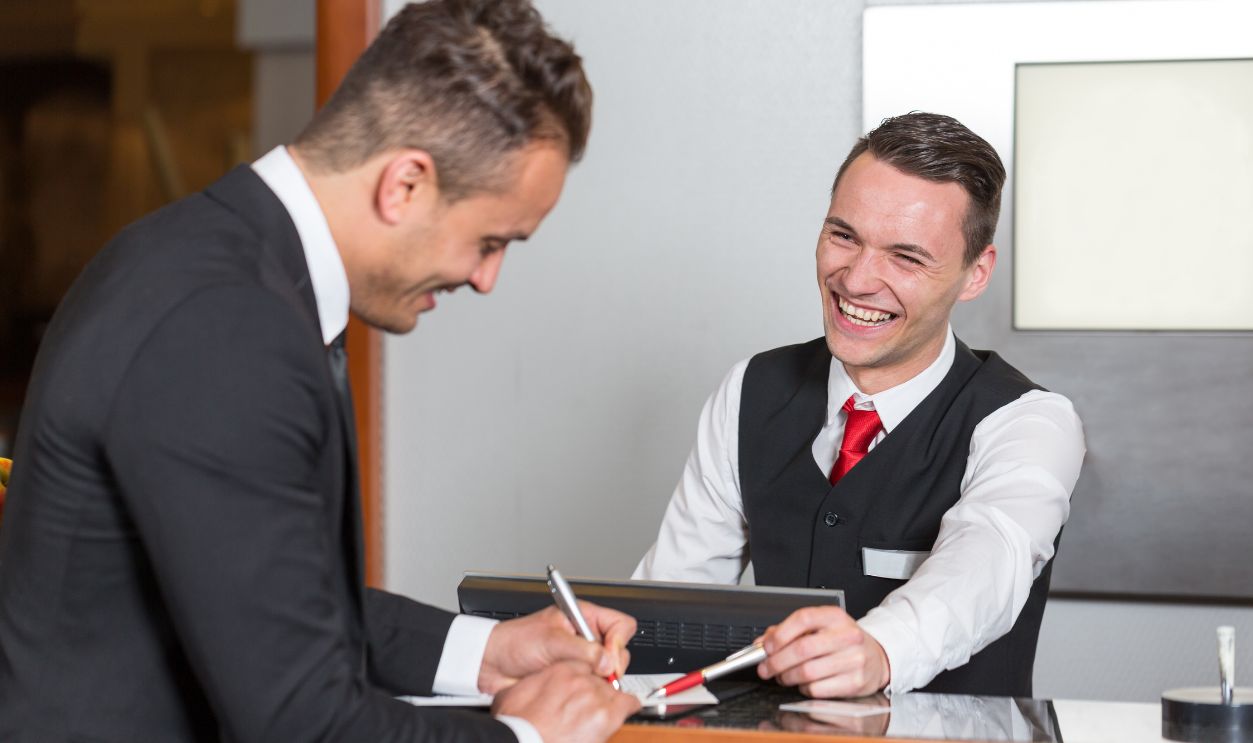 Receptionist at hotel reception assisting a guest 