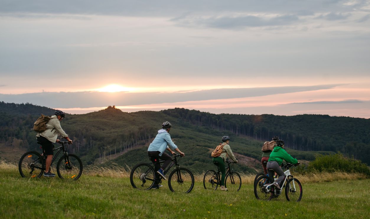 Family riding bicycles at sunset in mountains. Cycling trip during autumn day.