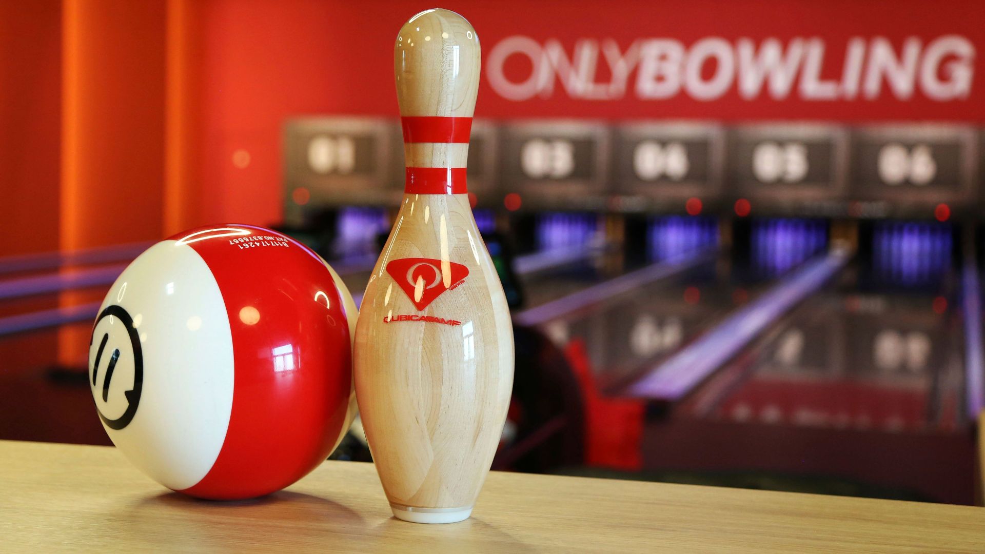 Close-up of a bowling pin and ball in a lively bowling alley setting.