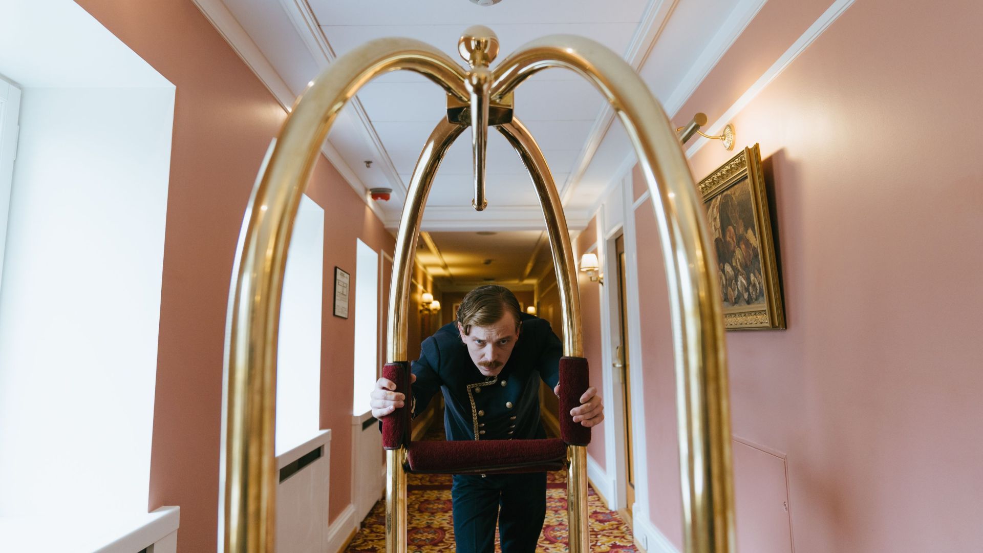 A bellboy pushes a luggage cart down a luxurious hotel corridor, embodying service and elegance.