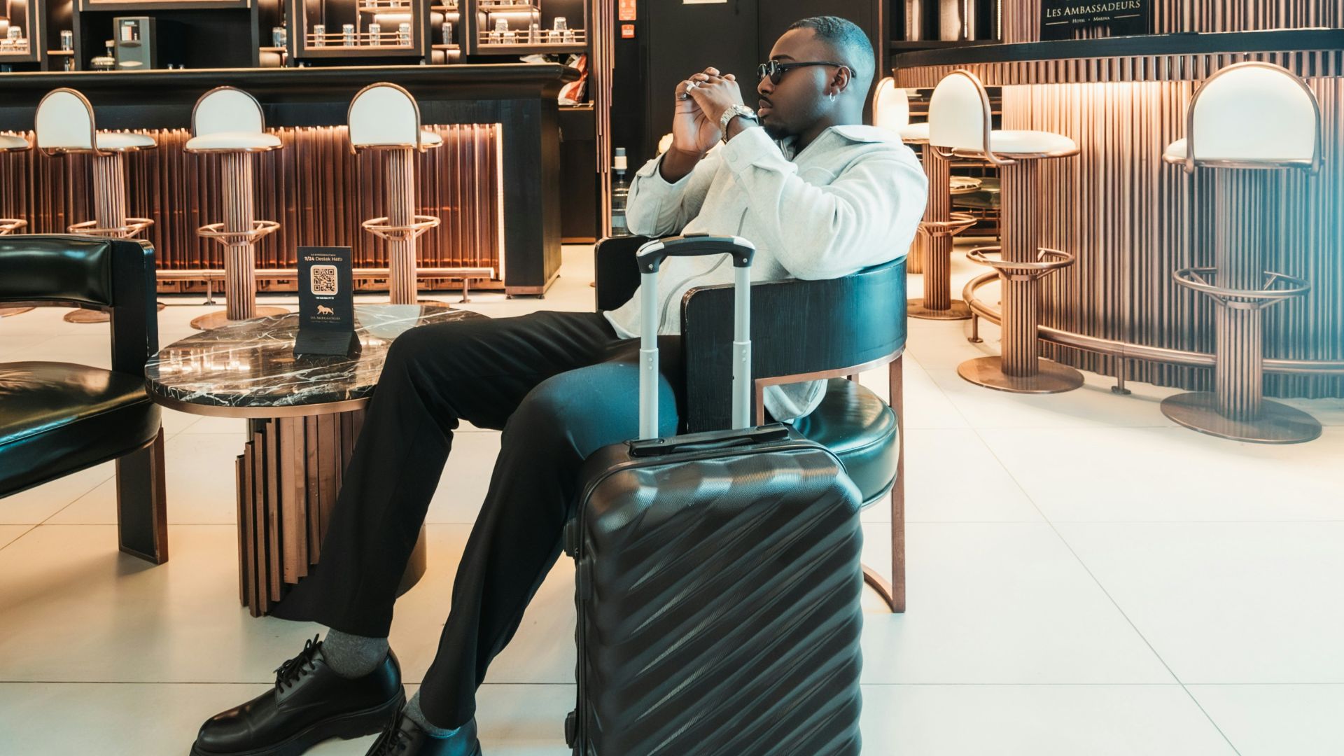 Man sitting with suitcase in stylish hotel lobby