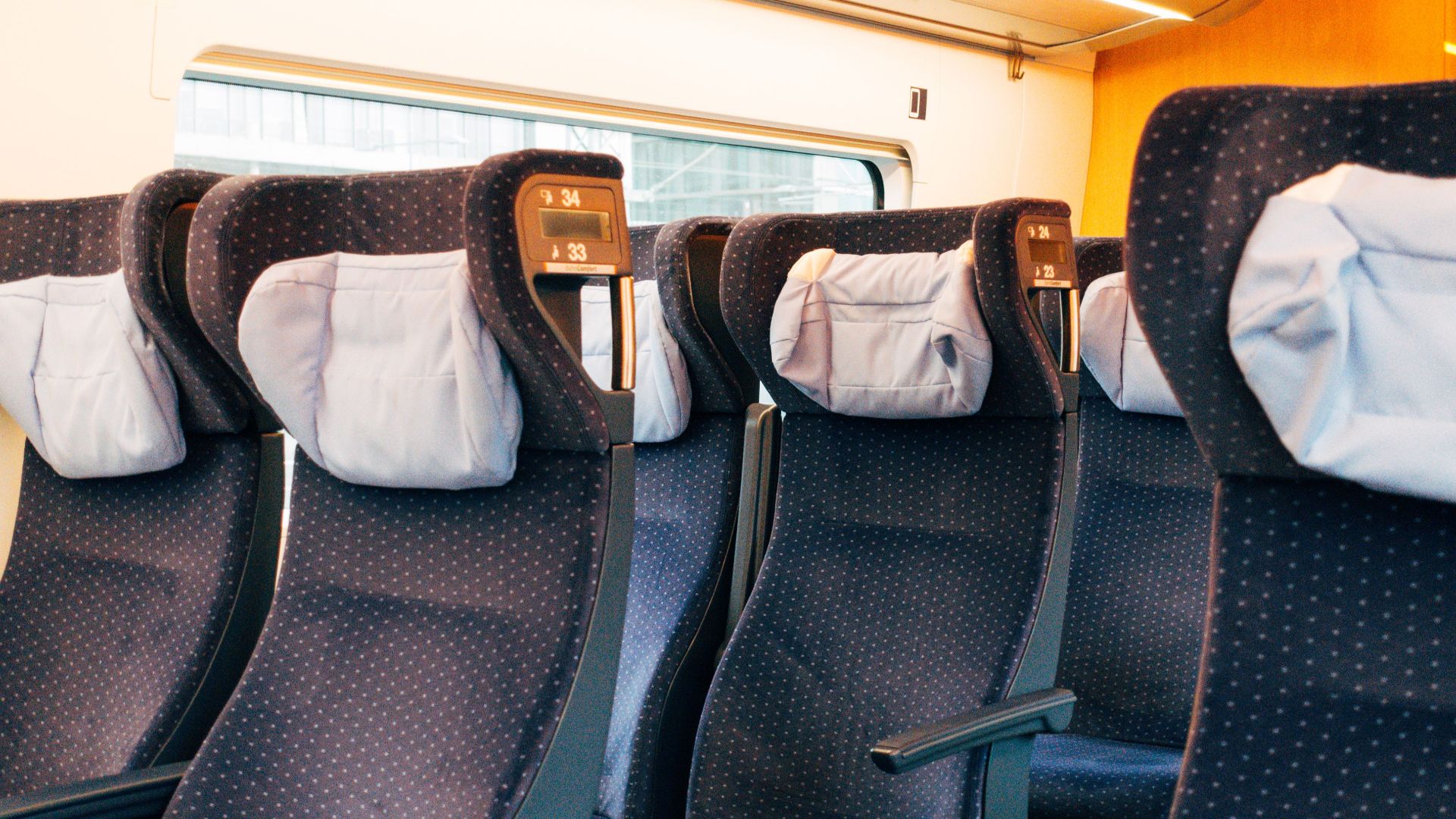 Interior view of modern train seats featuring polka-dot upholstery and headrests.