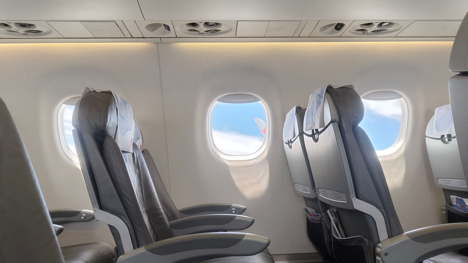 Interior of an empty airplane cabin featuring window view of sky and clouds, perfect for travel theme.