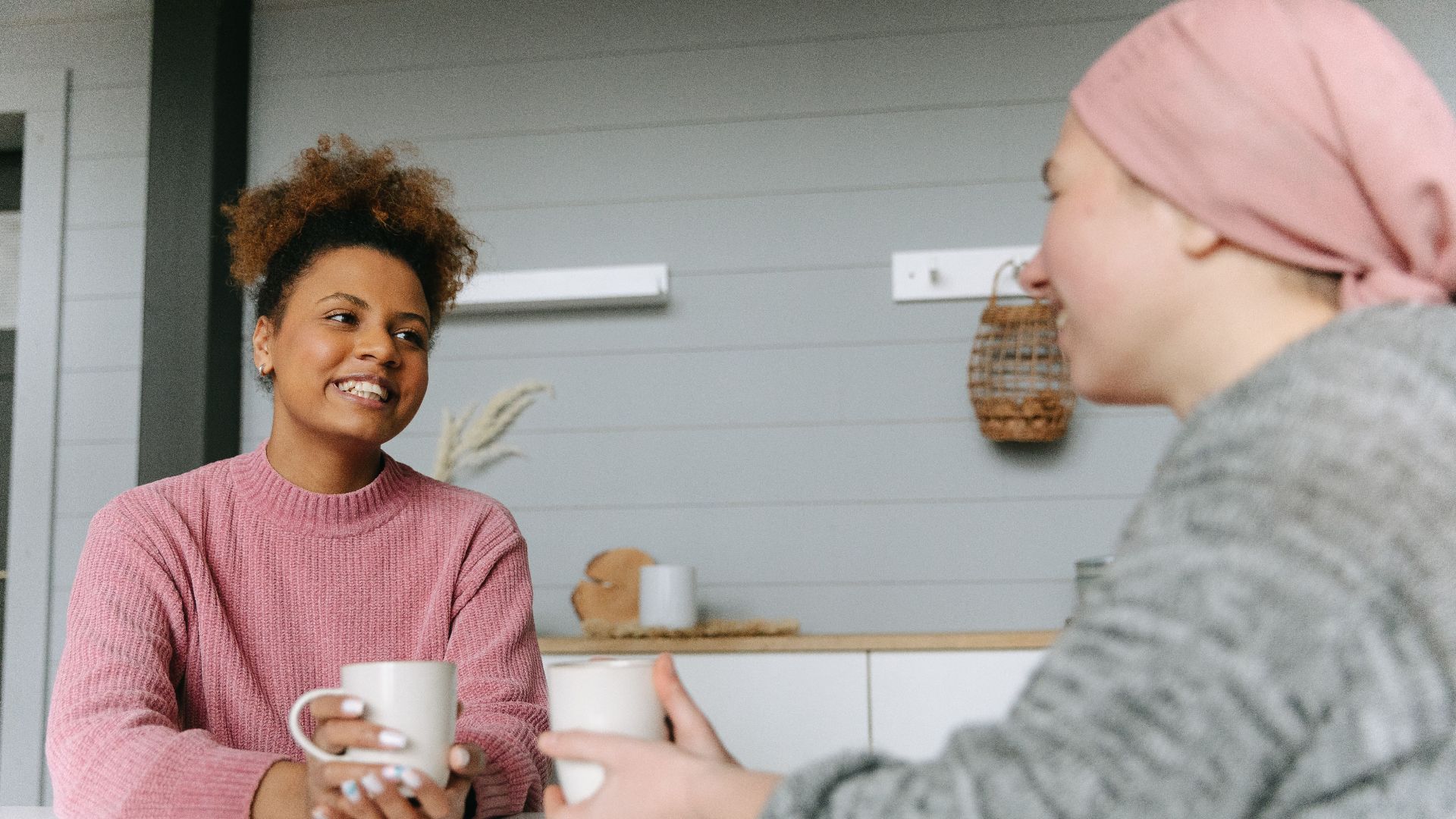 Two women share a joyful coffee moment at home, embodying friendship and warmth.