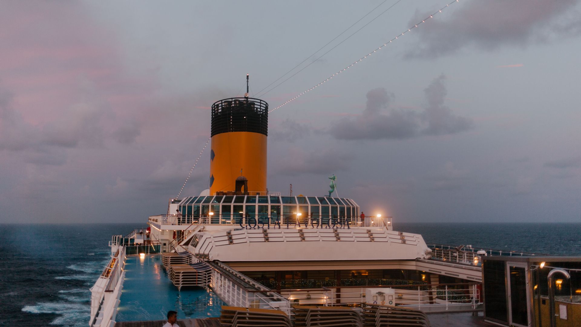 A cruise ship sails peacefully at twilight, with a beautiful ocean backdrop and soft evening lights.