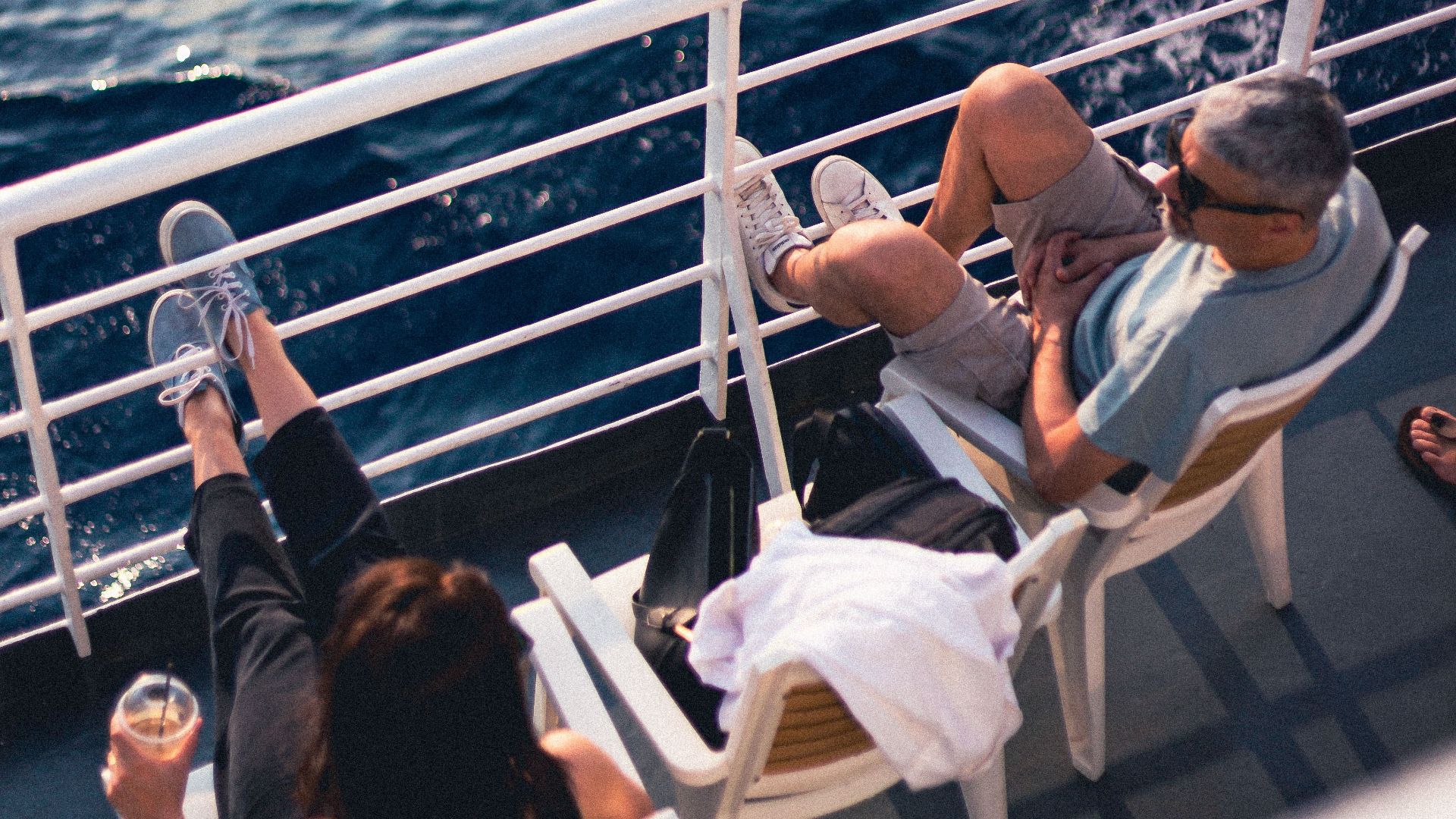 Couple relaxing on a cruise ship deck, enjoying the serene ocean view on a sunny day.