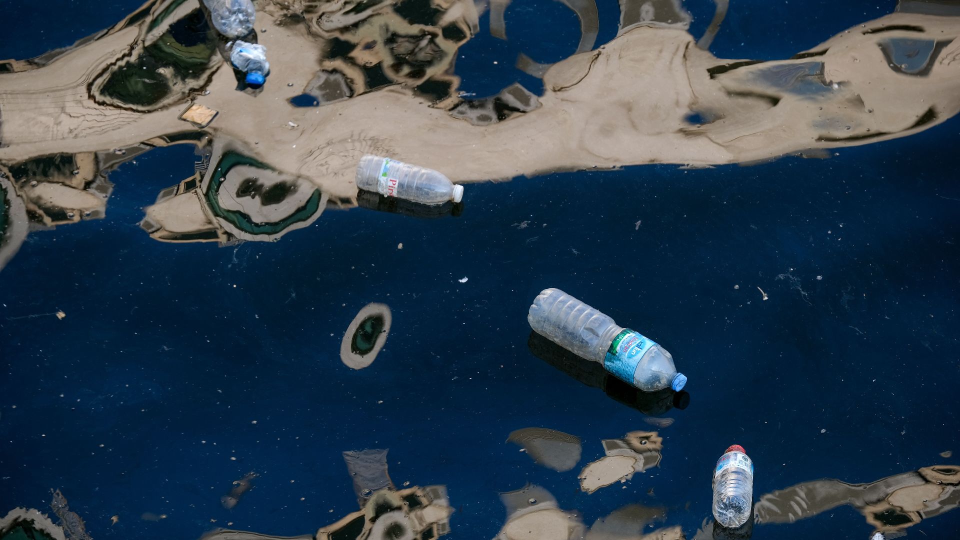 Plastic bottles floating in dark polluted water illustrating environmental pollution.