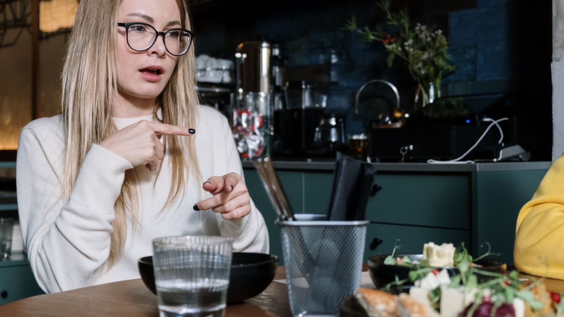 Woman using sign language while dining at a café, with focus on gesture communication.