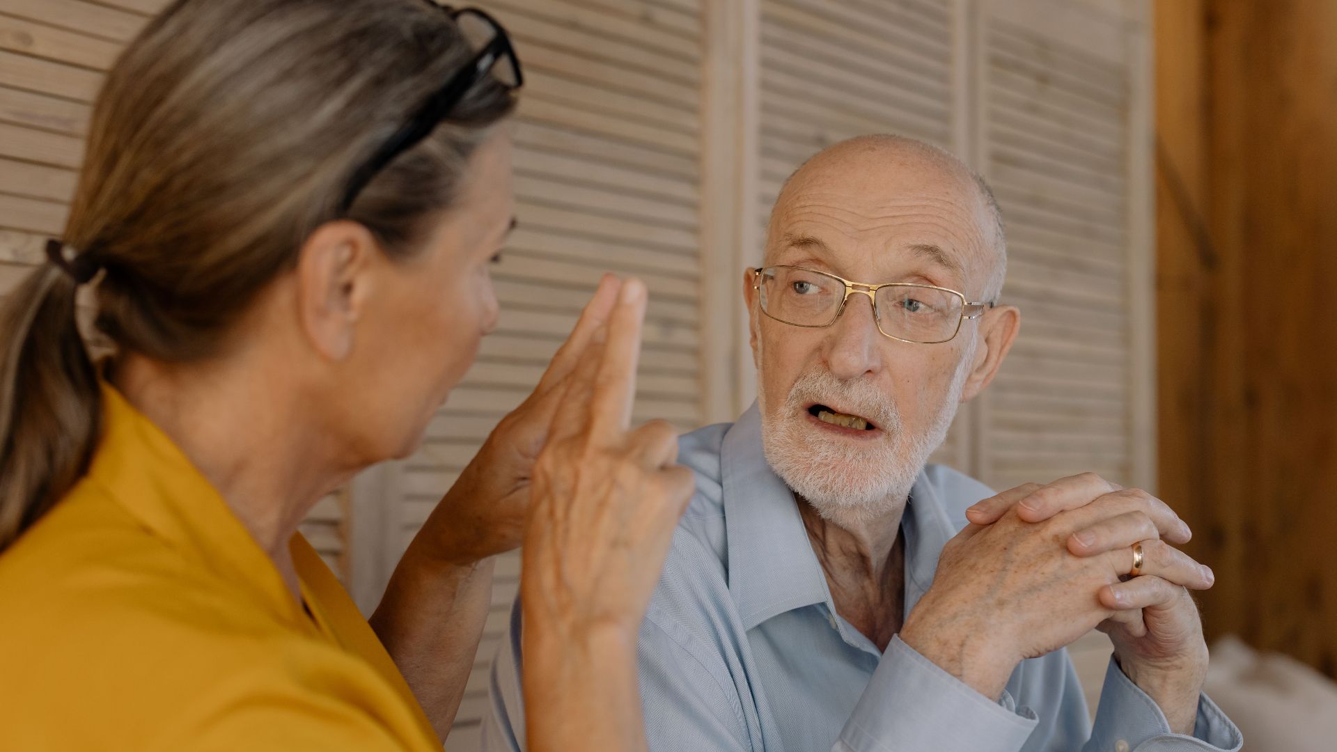 Elderly couple having an engaging conversation indoors, showcasing connection and emotion.
