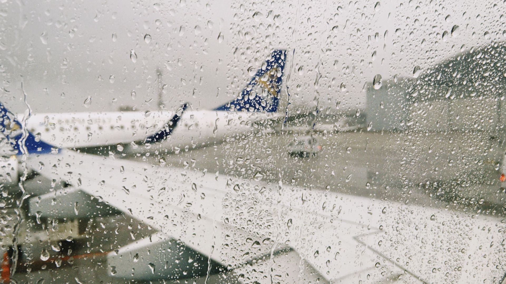Raindrops on airplane window with a view of the airport in Almaty, Kazakhstan.
