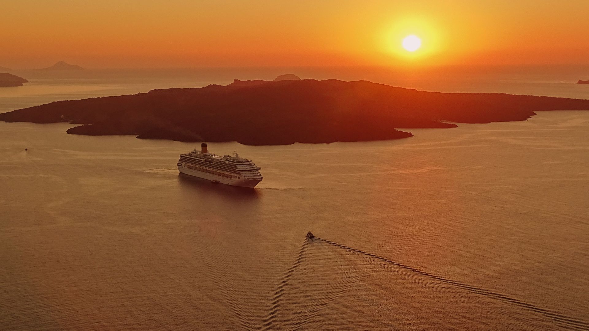 A breathtaking sunset view of a cruise ship near the island of Santorini, Greece.