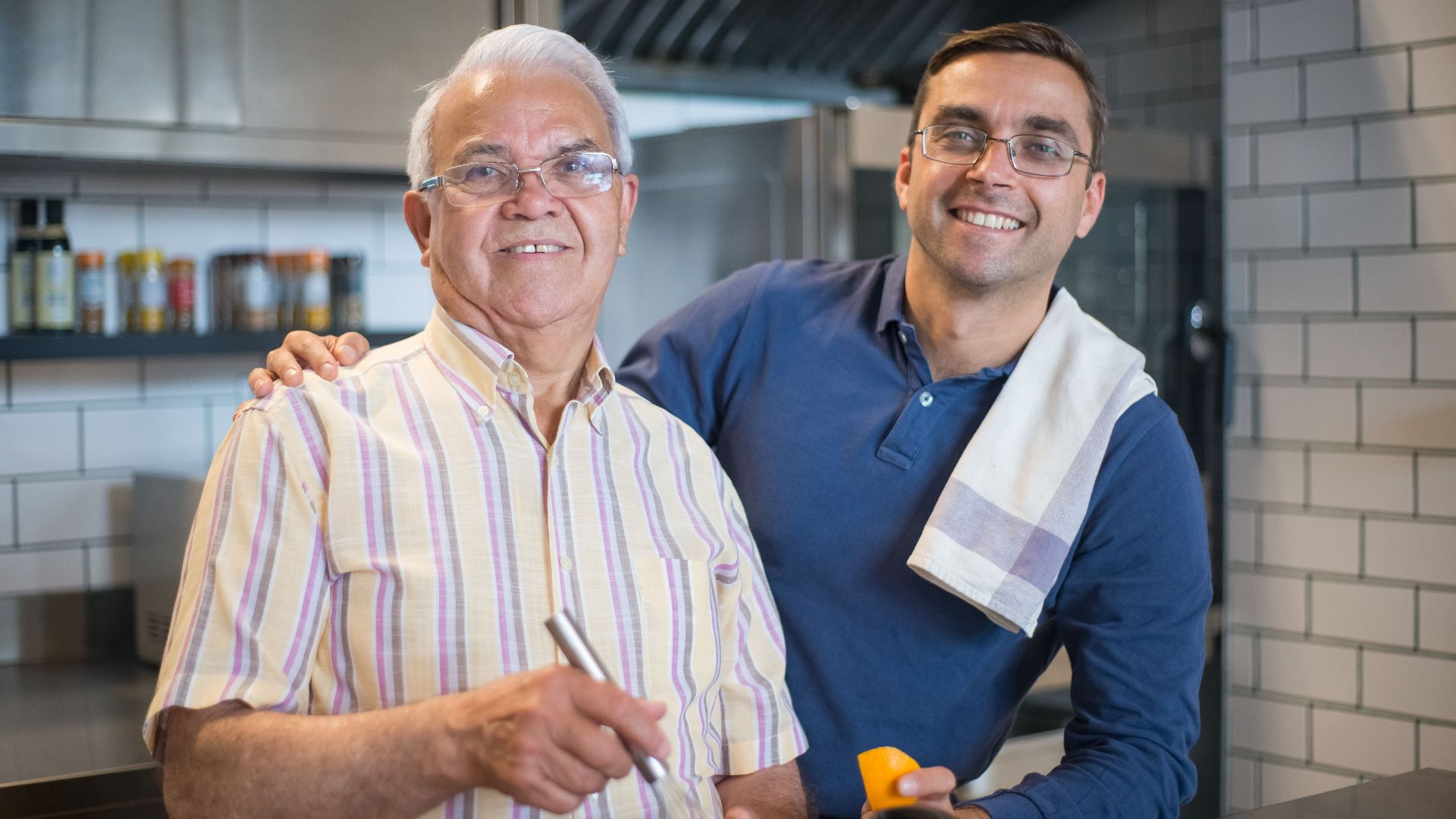 A father and son enjoy bonding time while cooking in a modern kitchen.