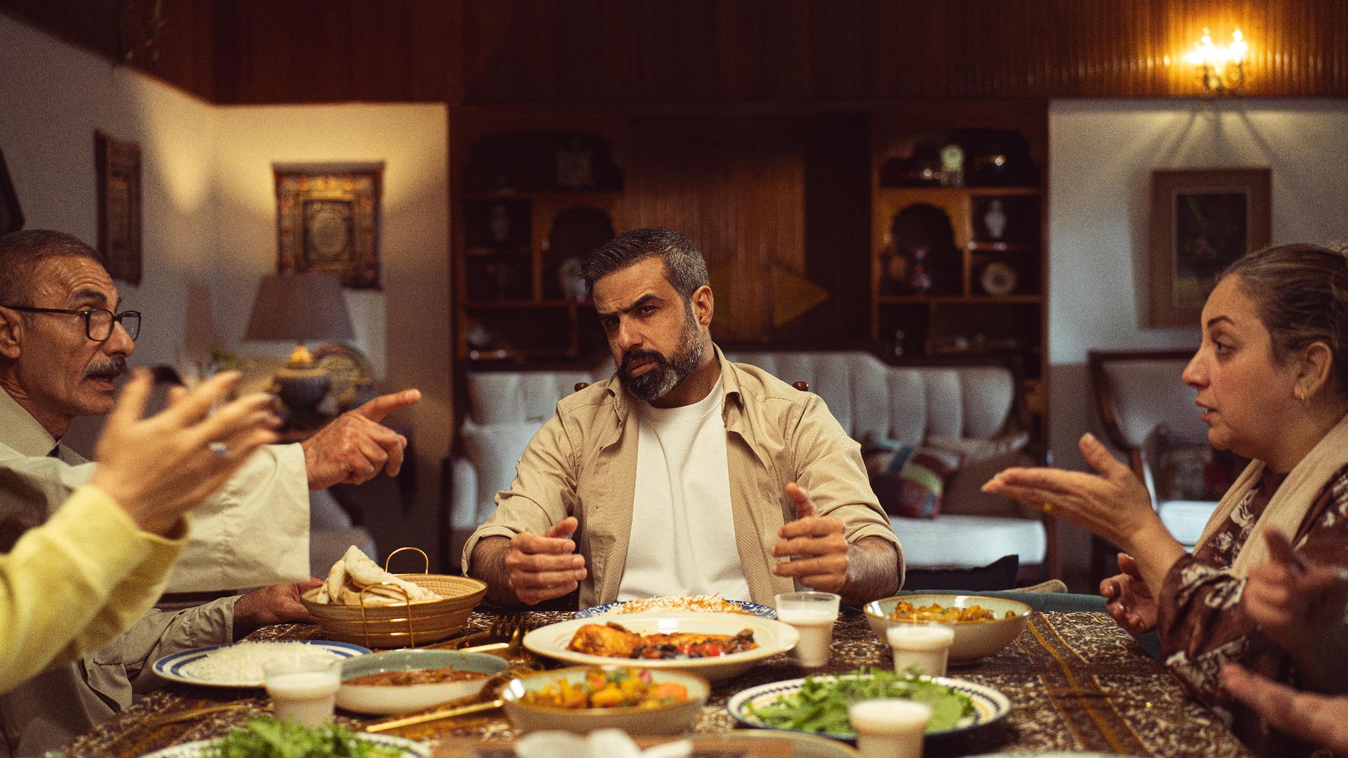A family gathering during dinner with a lively discussion at an indoor setting, showcasing Middle Eastern cuisine.