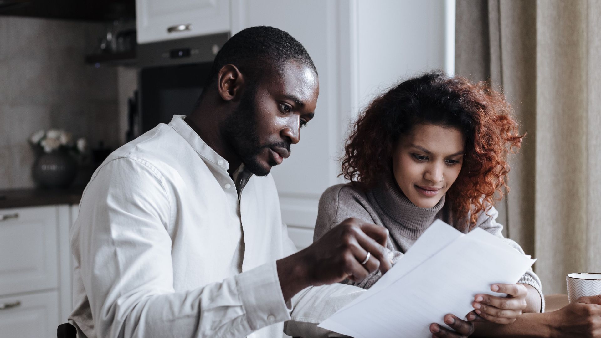 Couple working together on documents at home interior using a laptop.