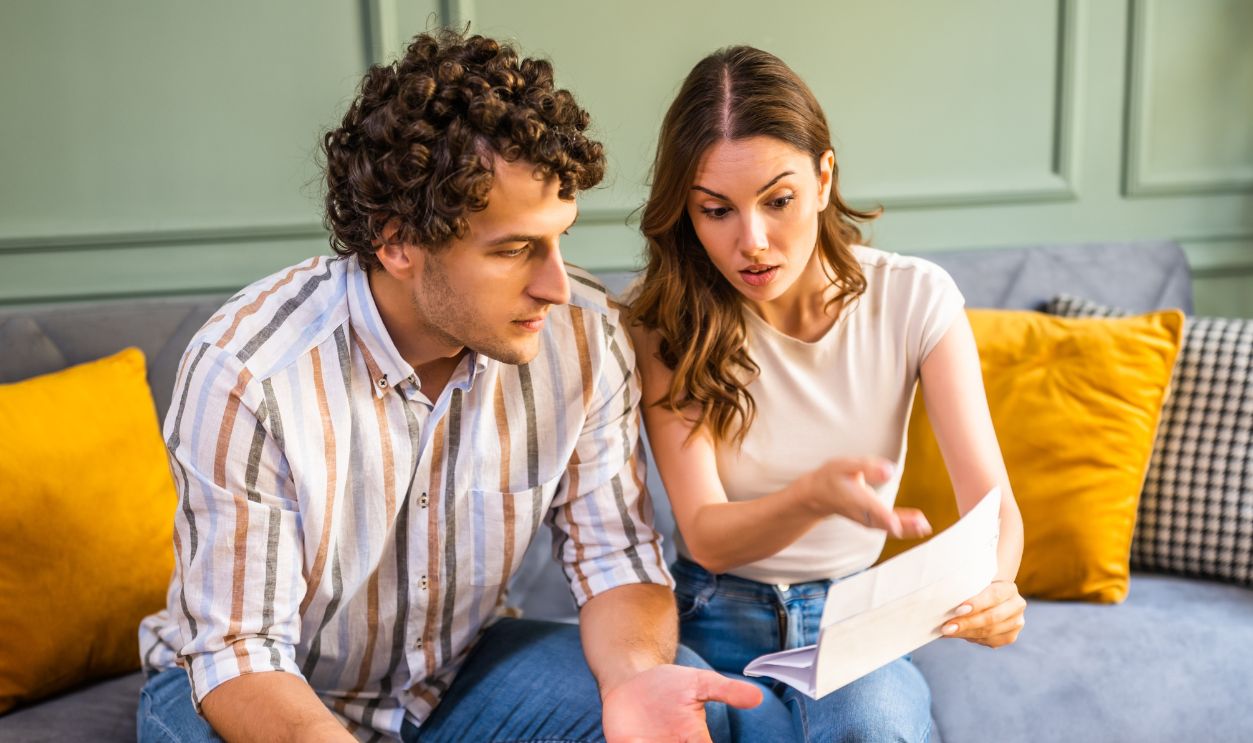 Shutterstock-2690420477, Couple discussing home finance while checking bills. They are checking financial documents and calculating family budget in living room.