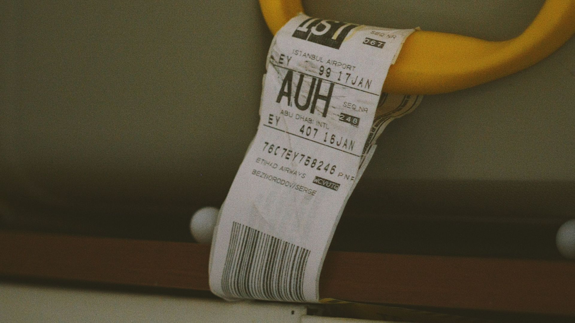 Close-up of a yellow suitcase handle with a visible travel tag and barcode, ideal for travel themes.