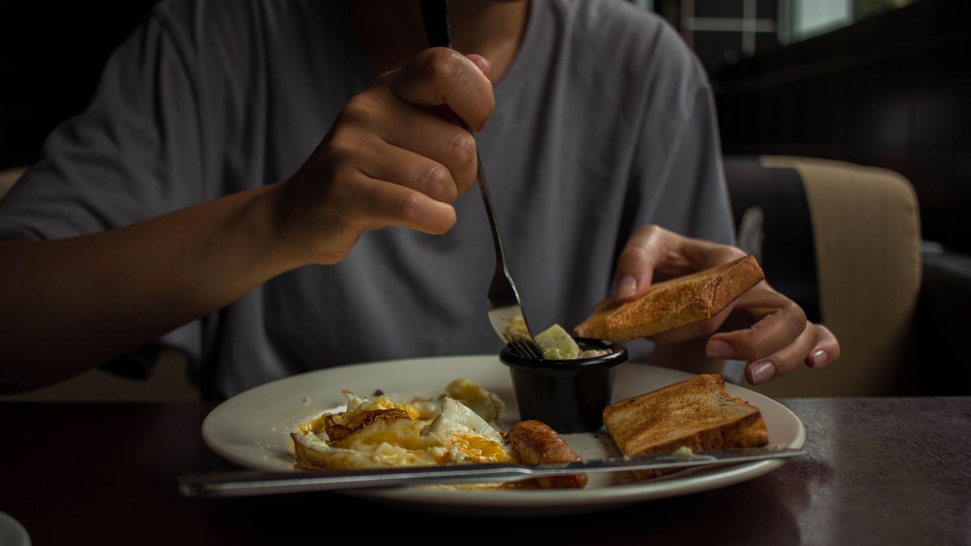 A person enjoying a breakfast with eggs and toast at home in a cozy setting.