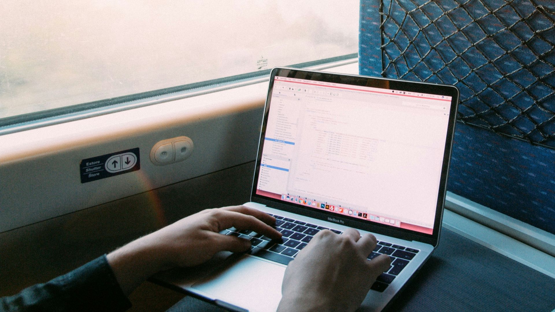 person using macbook pro on blue and white chair