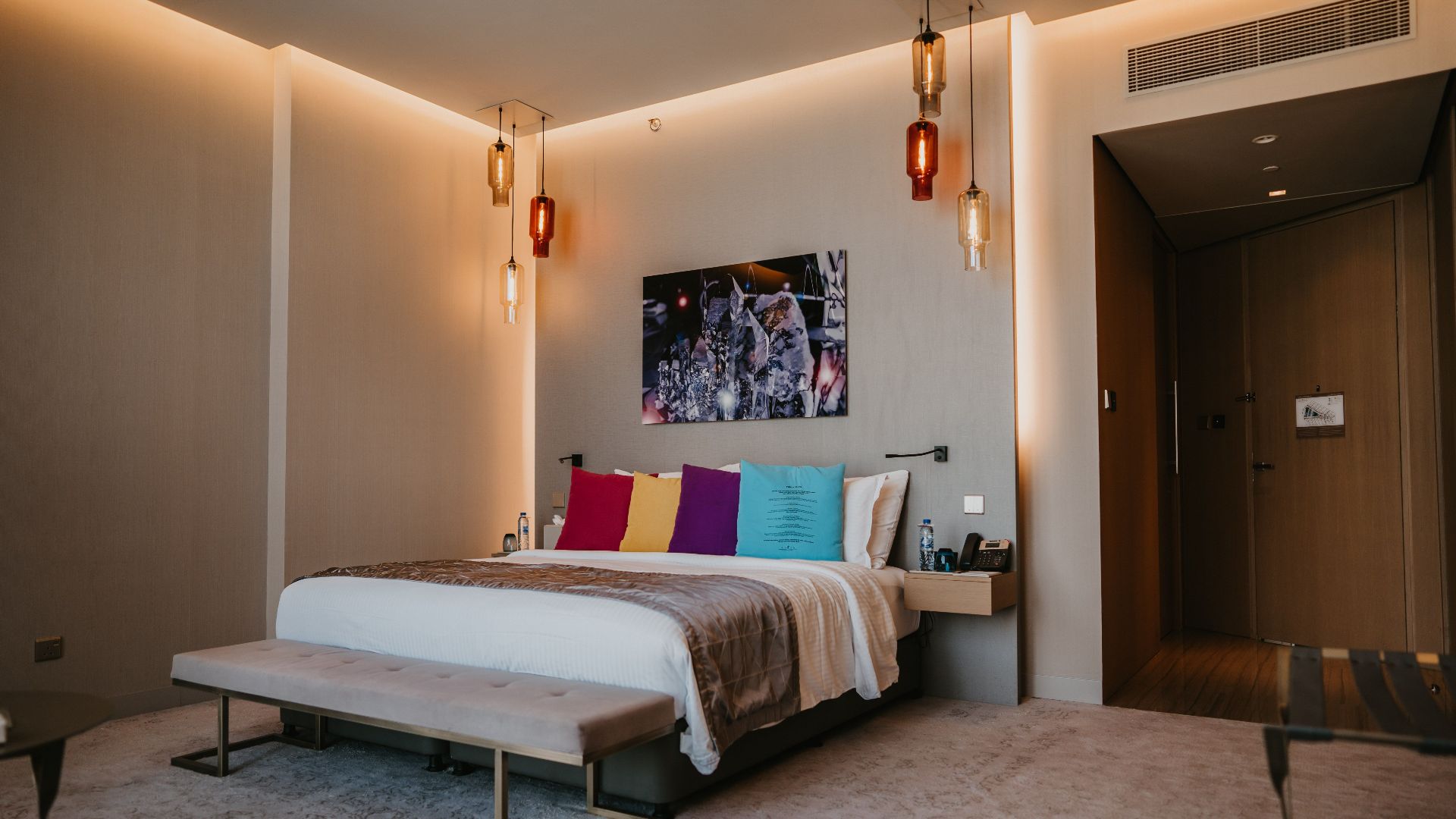 Spacious modern bedroom with colorful pillows and elegant decor in a luxury Dubai hotel.