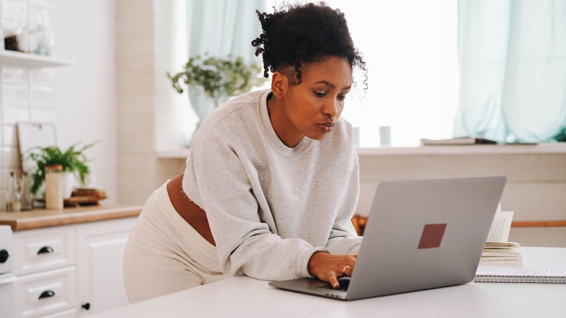 A woman using a laptop in a cozy home setting, focused on online education.