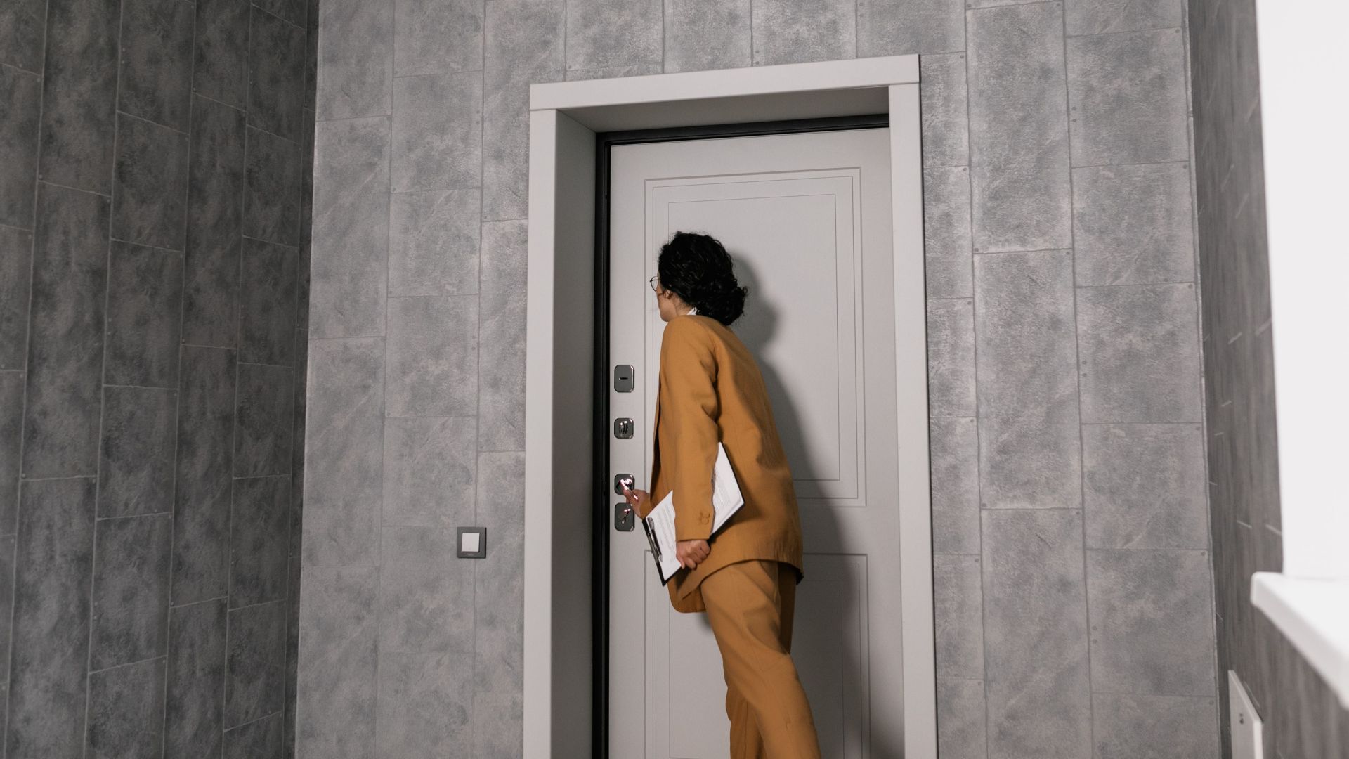 Real estate agent in business attire inspecting a modern home's entrance.