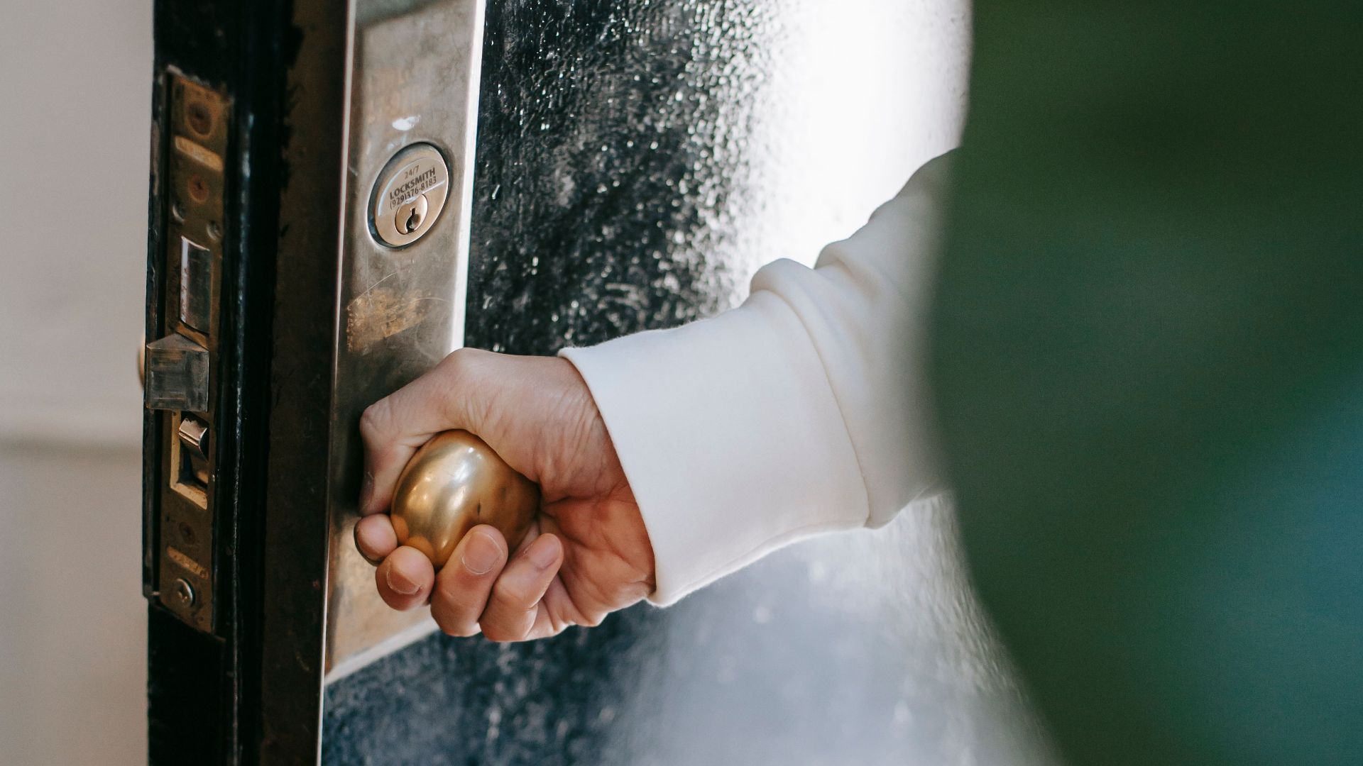 High angle of crop unrecognizable person holding round shaped handle while opening door at home