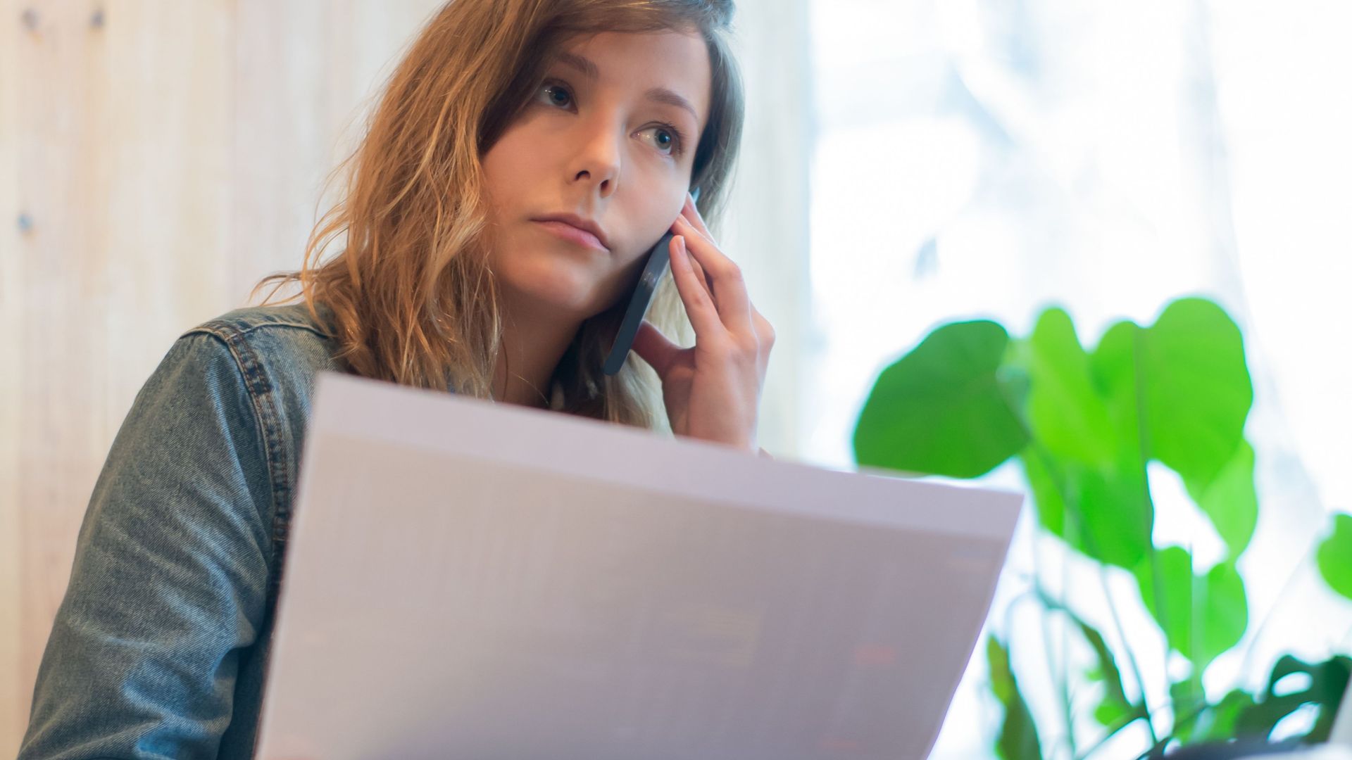 Focused businesswoman reviewing documents in a bright office with natural light.