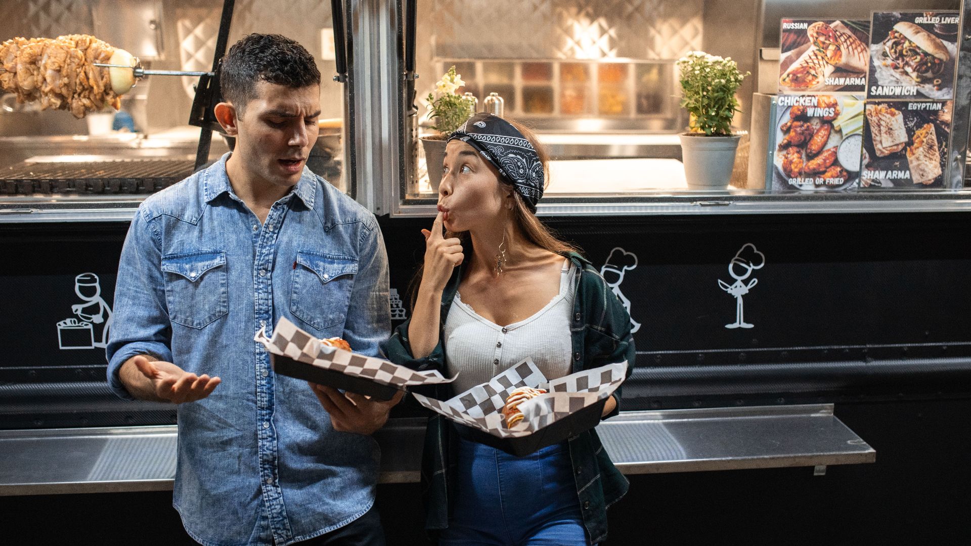 A couple enjoys street food from a food truck at night, sharing fun moments.