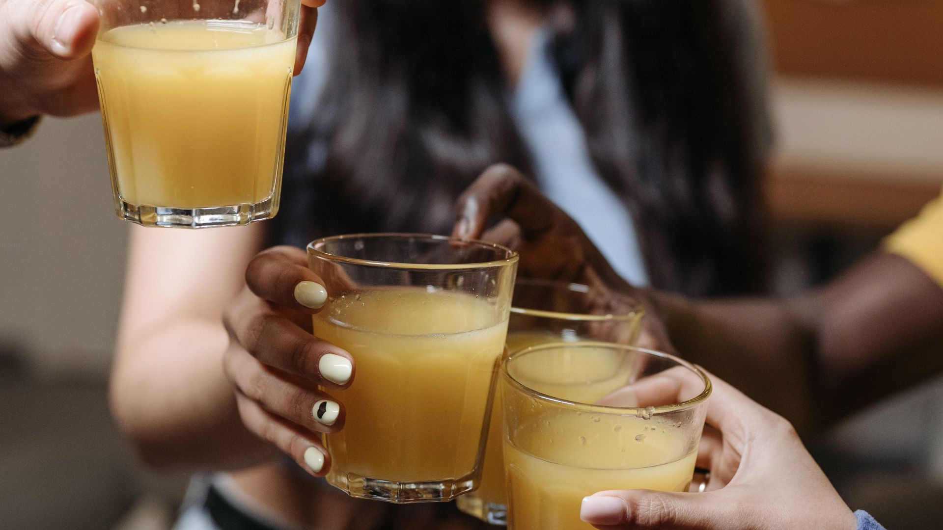 A group of friends toasting with glasses of juice indoors.