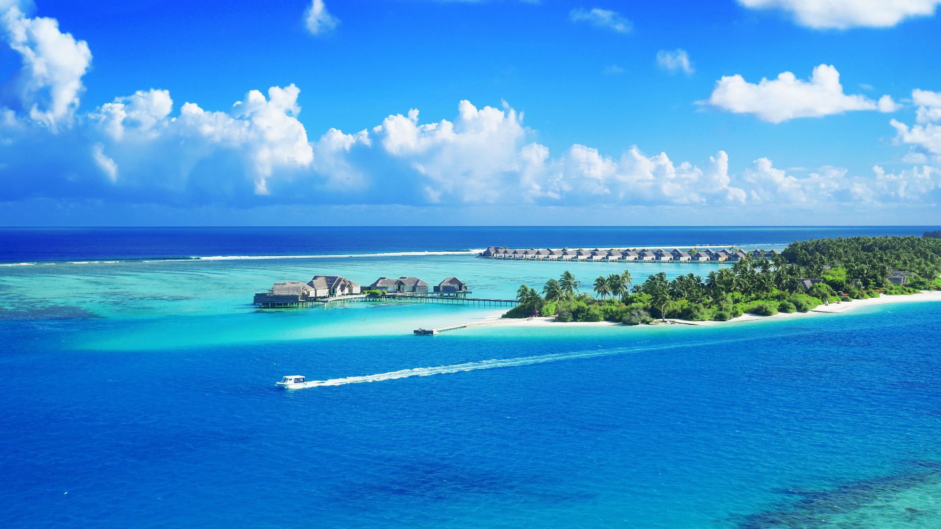 Crystal clear waters surround a luxurious Maldives resort under a bright blue sky.
