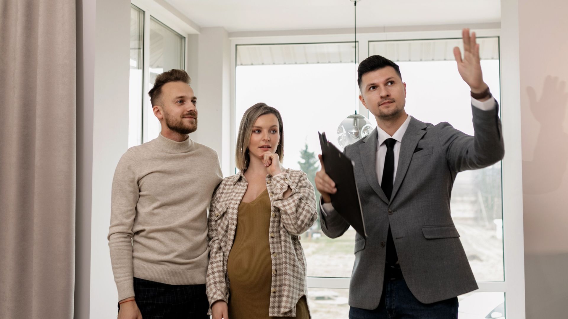 A pregnant woman and her partner explore a new house with a real estate agent.