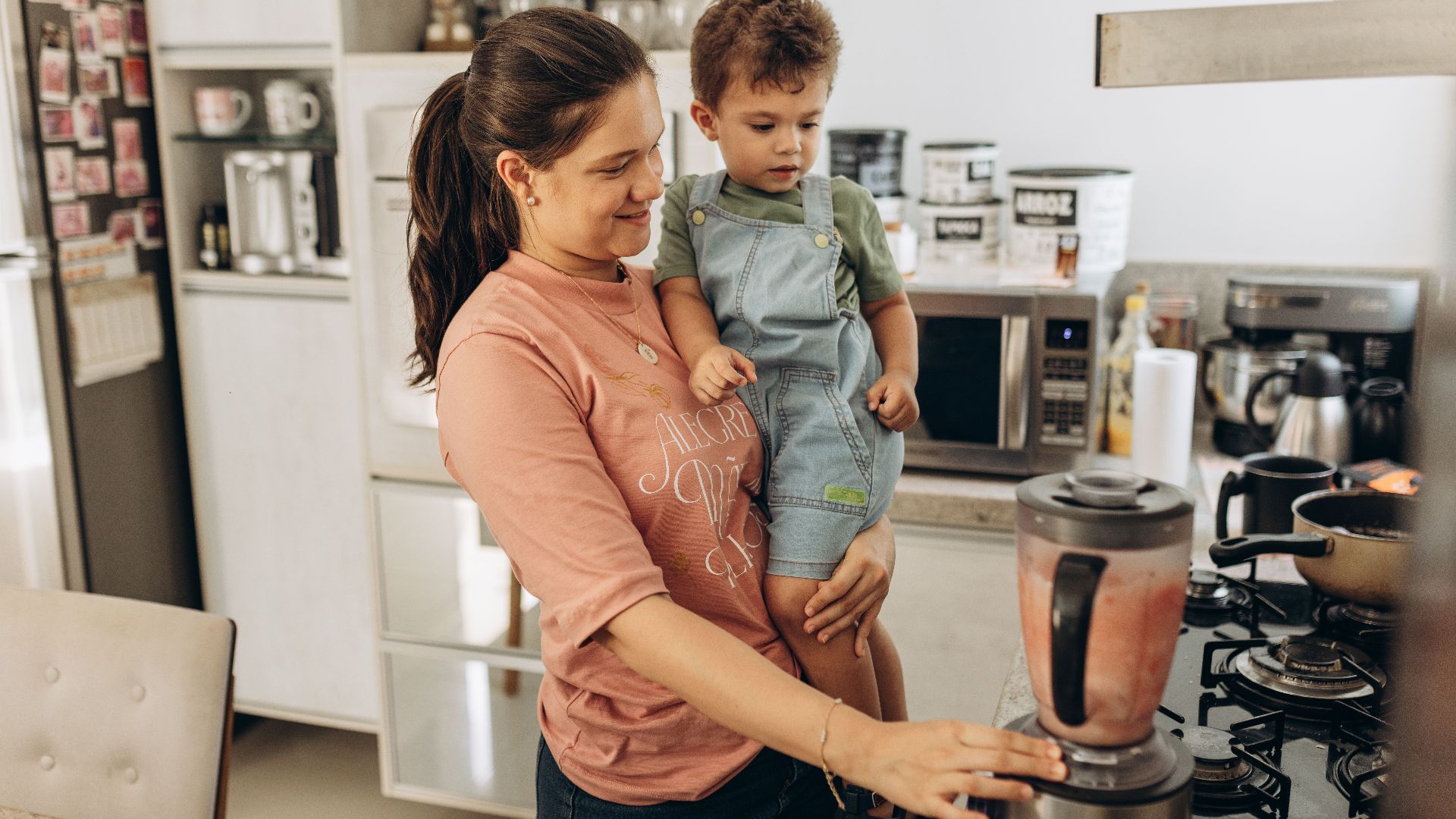 Mother and child using a blender together in a cozy kitchen setting.