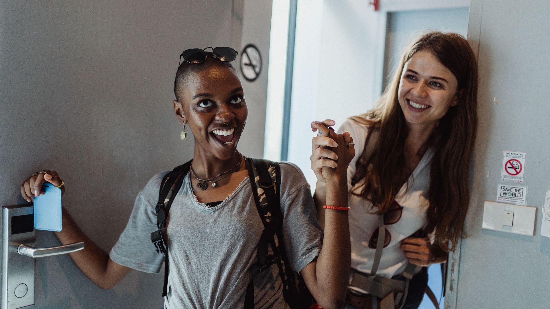 Two cheerful women entering a modern room, capturing moments of fun and friendship.
