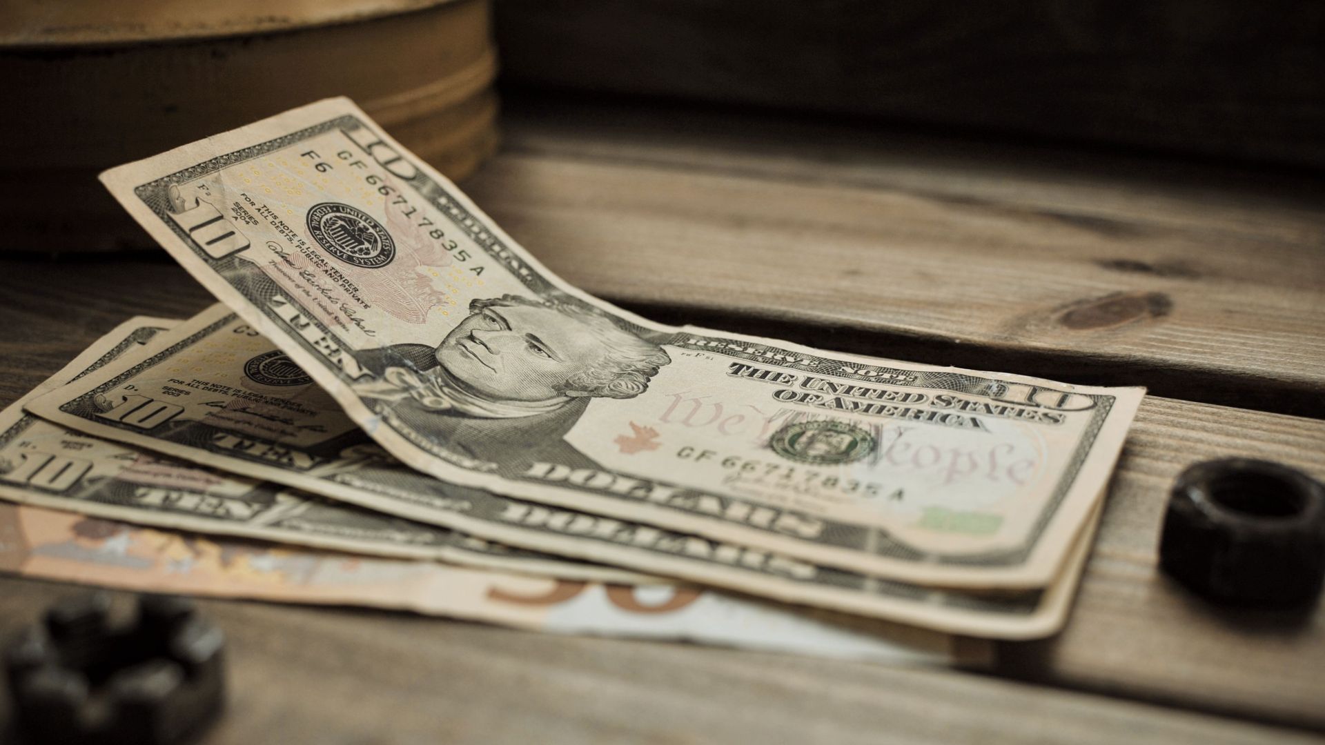A stack of US dollar bills on a rustic wooden table close-up view.
