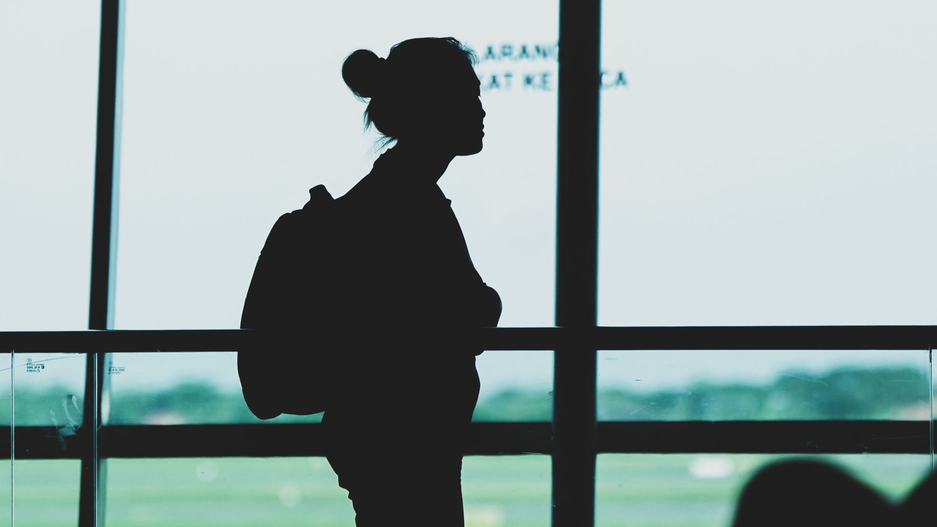 Silhouette of a woman with a backpack standing at Surabaya airport terminal, Indonesia.