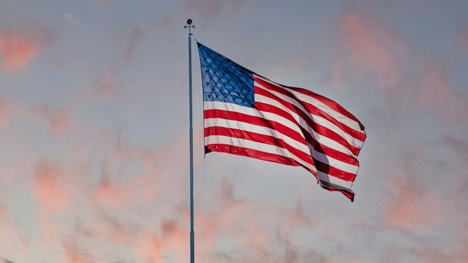 us a flag on pole under cloudy sky