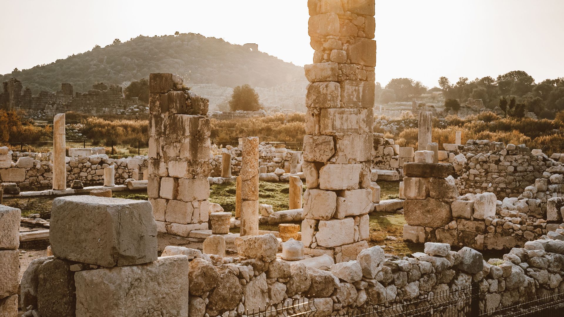 Explore the serene beauty of ancient ruins with towering columns at sunset, evoking history and tranquility.