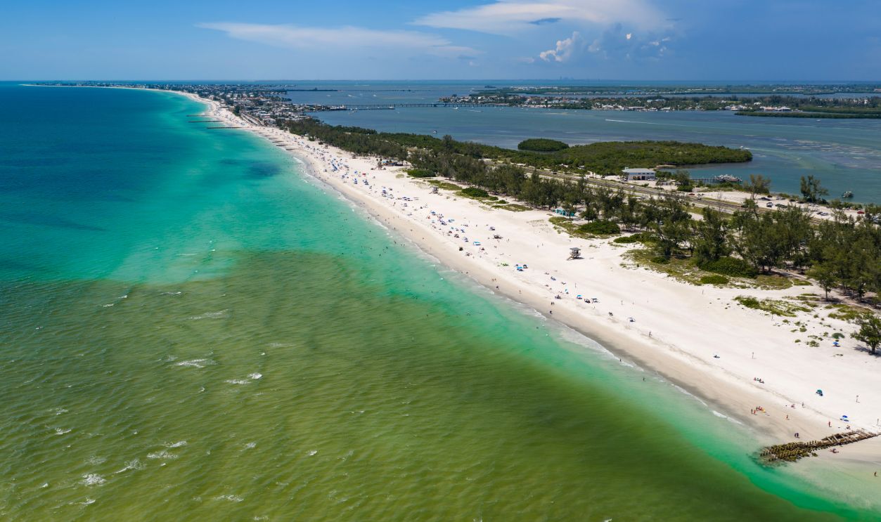 Aerial view northward of the estuarine plume flowing into the beach waters of Anna Maria Island, Florida. This green tannin-rich water meets the turquoise waters of Coquina Beach and makes a striking contrast of colors.